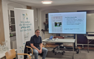 Ein Mann sitzt auf einem Stuhl in einem Raum vor einer Leinwand.