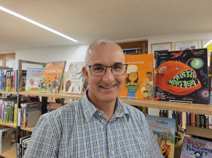 Mann steht im Raum uns spricht über ein projiziertes Bild an der Wand